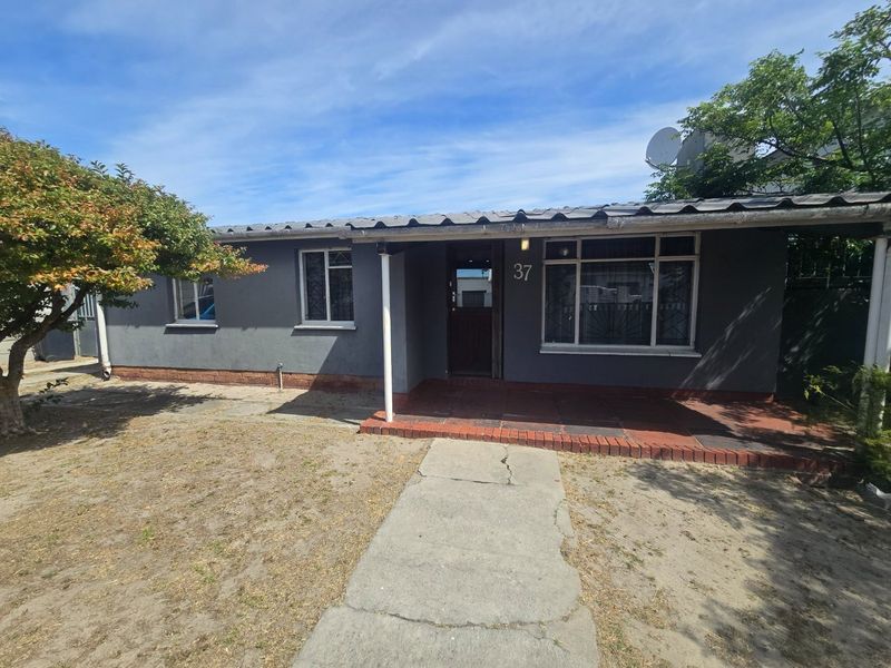 Front elevation of a single-story house featuring a covered porch, tiled roof, and a concrete walkway leading to the entrance.