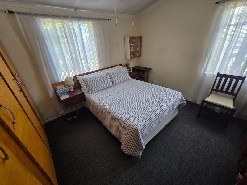 A functional bedroom featuring carpeted flooring, built-in wardrobe storage, and dual windows with curtain rails.