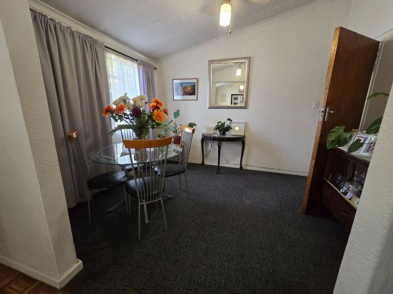 A dining area featuring dark carpeting and a ceiling light fixture, offering a functional space ready for modern updates and cosmetic improvements.