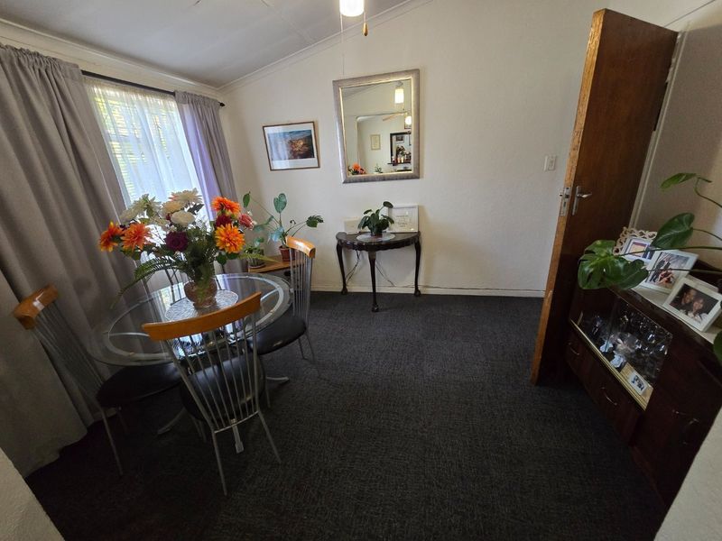 A dining room featuring carpeted flooring, coved ceilings, and a timber door, providing a functional space for meals.