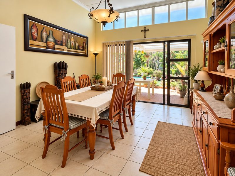 A bright dining room featuring tiled flooring, clerestory windows for natural light, and a sliding glass door providing direct access to the outdoor patio area.
