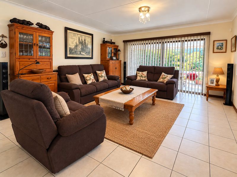 A well-maintained living room featuring neutral tiled flooring and large sliding glass doors that provide access to the outdoor patio area.