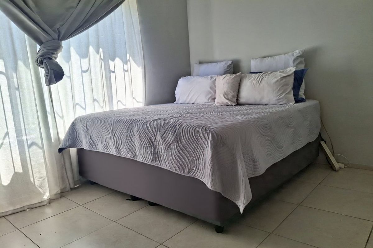 A bedroom featuring neutral wall tones and tiled flooring, providing a clean and functional space.