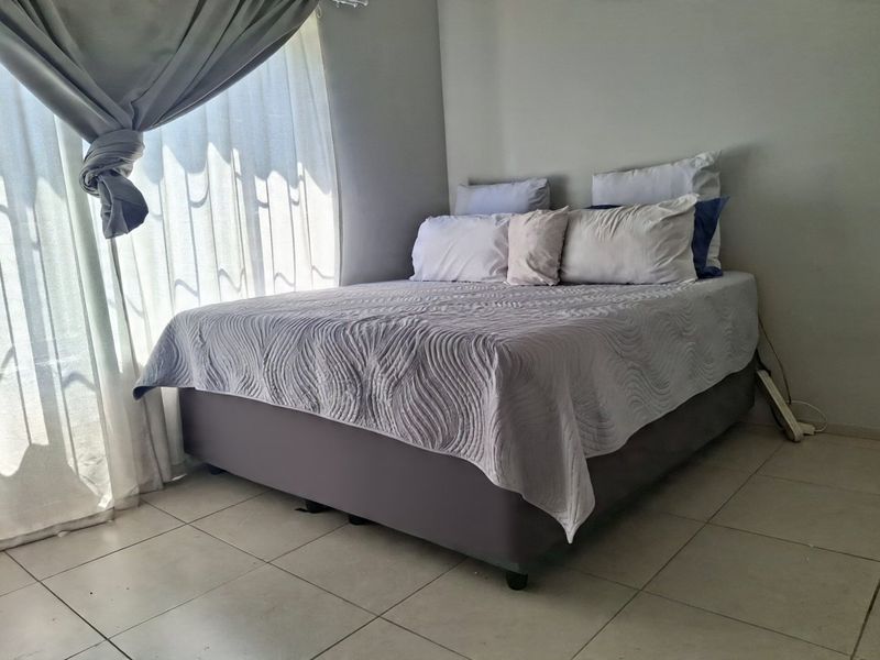 A bedroom featuring neutral wall tones and tiled flooring, providing a clean and functional space.