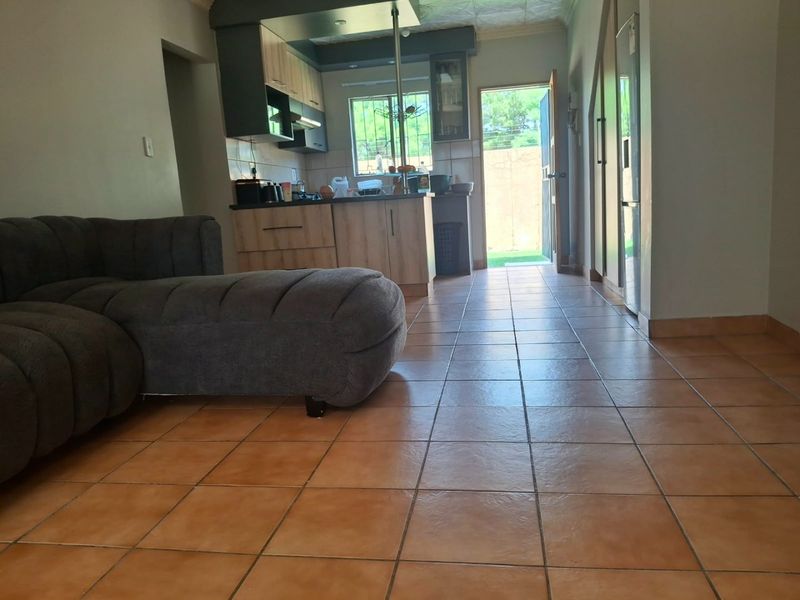 Open plan living area featuring tiled flooring and a functional kitchen with built-in cabinetry, leading directly to an outdoor space.