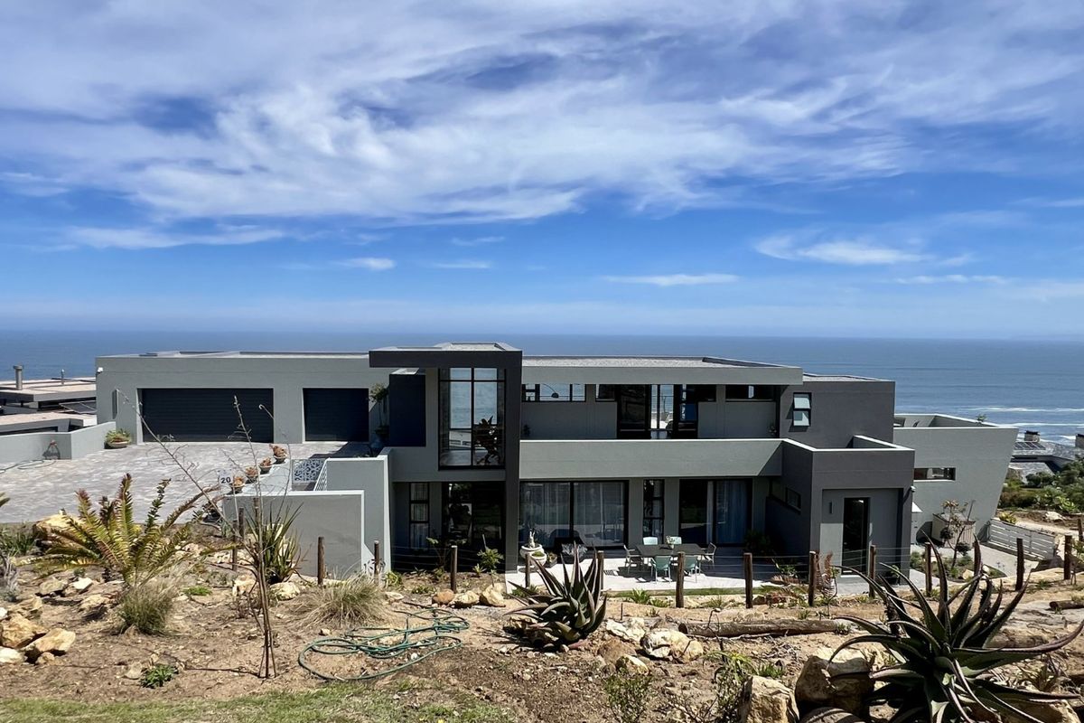Modern multi-level coastal residence featuring a flat roof, expansive glass windows, double garage, and a rear patio overlooking the ocean.