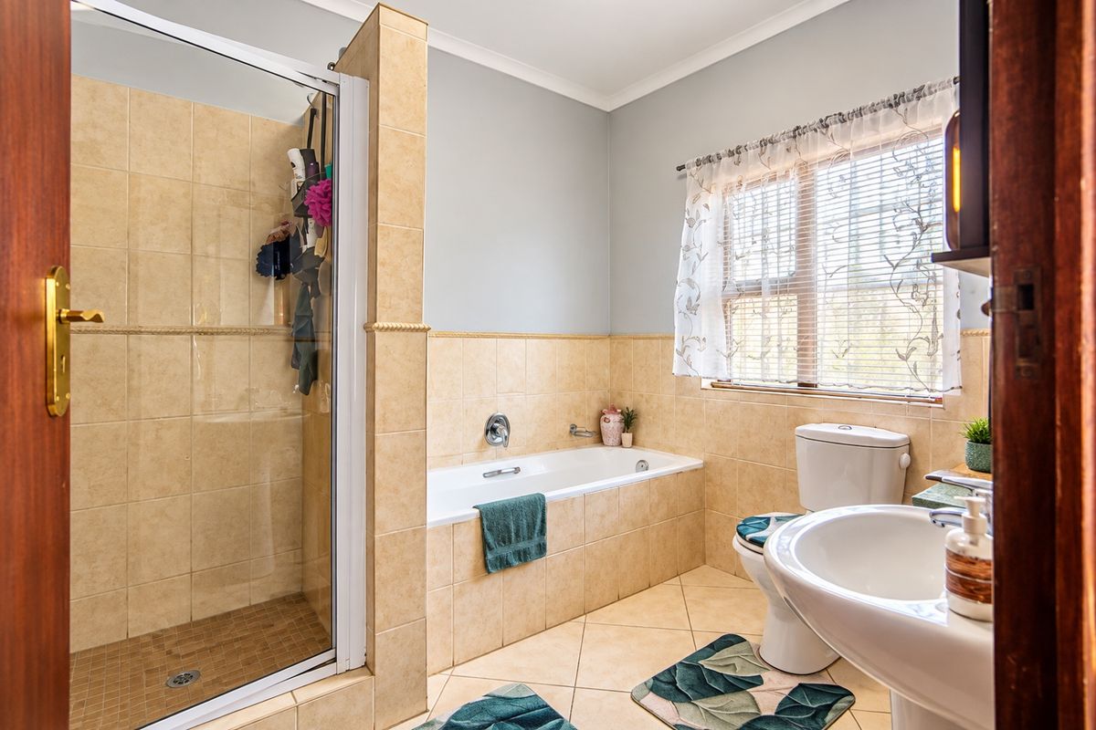 A functional bathroom featuring a separate shower enclosure, built-in bathtub, pedestal basin, and toilet with neutral tiled finishes.