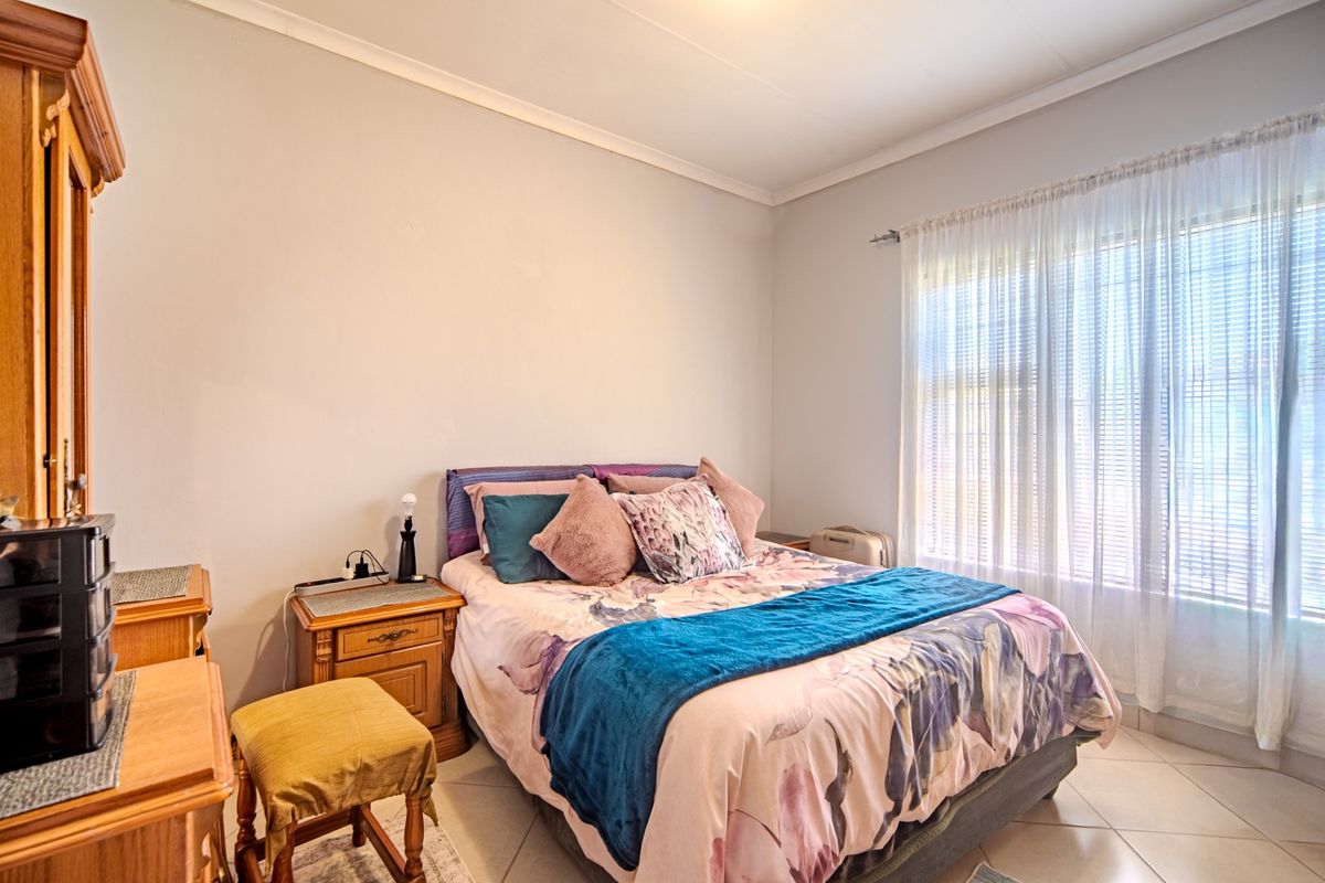 A well-lit bedroom featuring tiled flooring and neutral wall finishes, providing a comfortable and functional living space.
