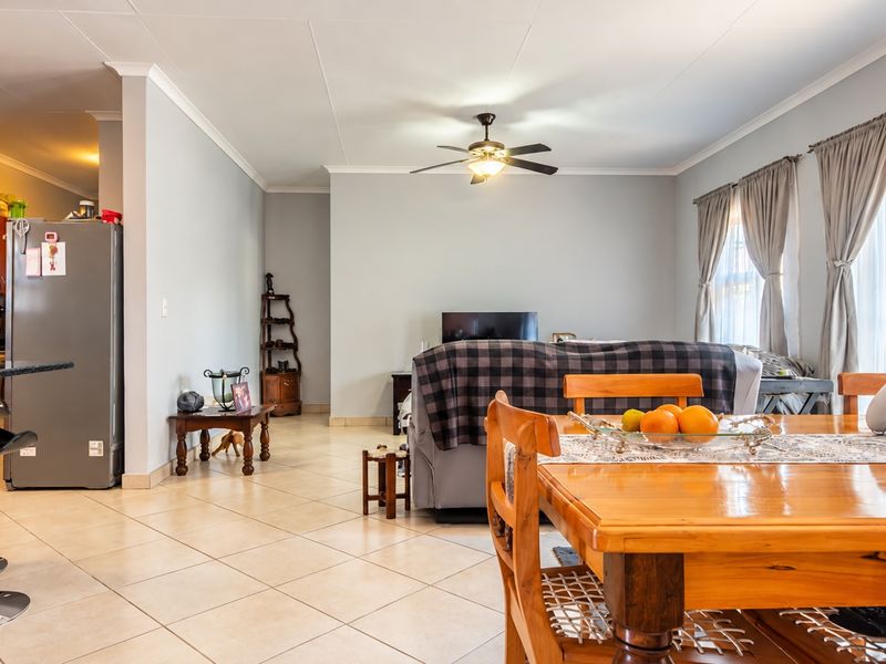 An open-plan living and dining area featuring neutral wall tones, tiled flooring, and a central ceiling fan, creating a functional and cohesive living space.