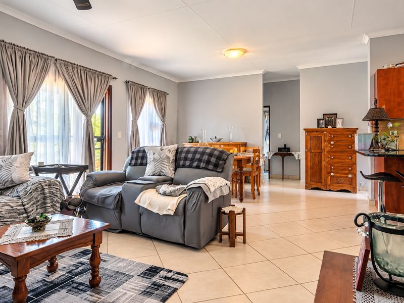 Spacious open-plan living and dining area featuring tiled flooring, a breakfast bar, and direct access to the outdoors through sliding glass doors.
