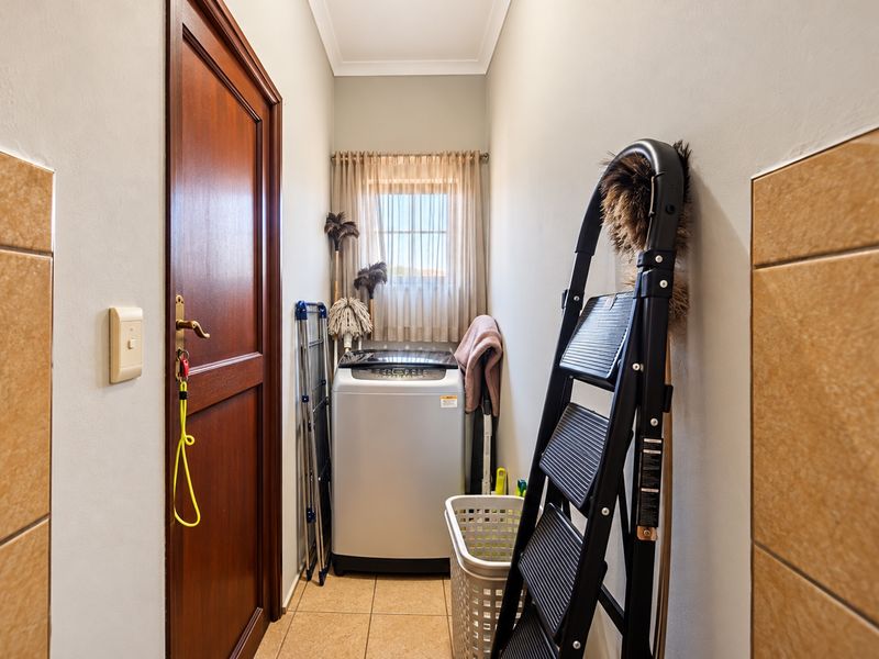 A functional laundry area featuring tiled flooring, a timber door, and a window, providing a practical space for household utility tasks.