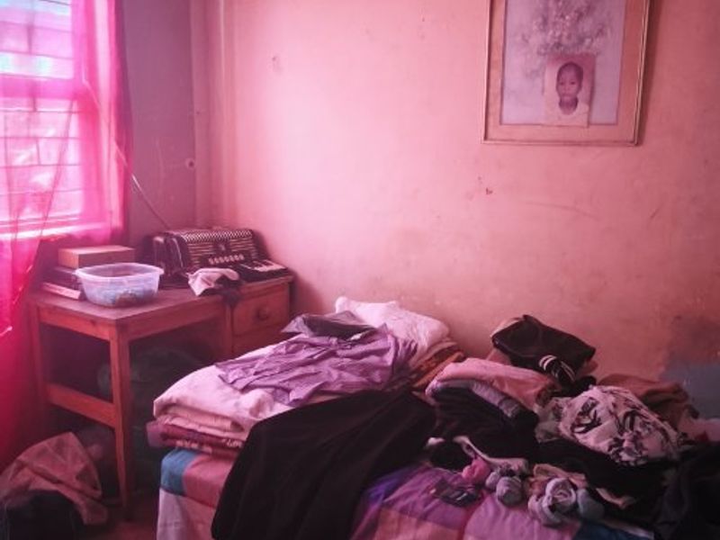 A bedroom featuring a window and basic wall finishes, currently requiring maintenance and cosmetic updates to improve the overall condition of the space.