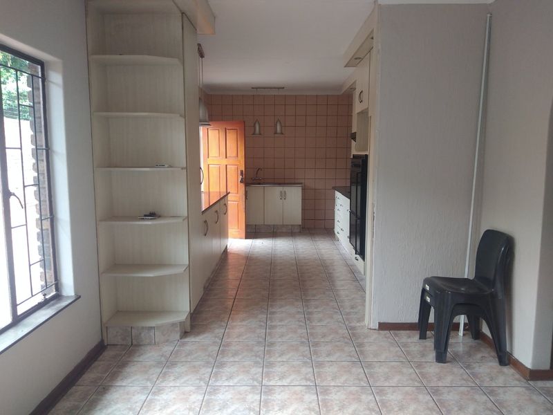A functional kitchen space featuring built-in cabinetry, tiled flooring, and a tiled splashback, offering a blank canvas for potential modern updates and renovation.