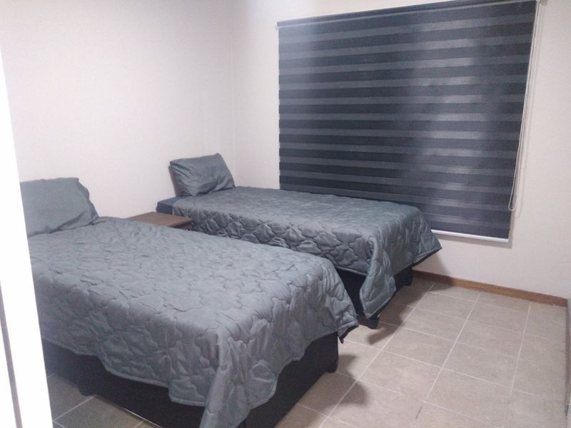 A functional bedroom featuring tiled flooring and modern zebra blinds, providing a neutral space ready for personalization.