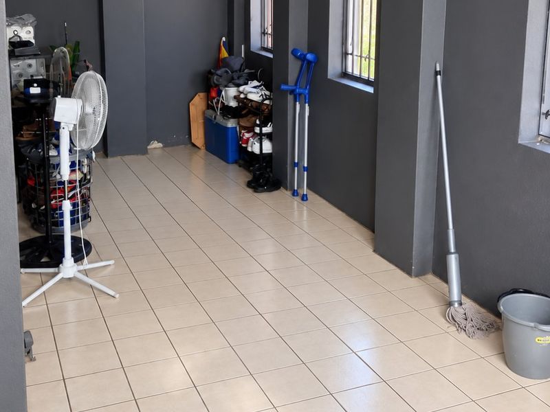 A functional utility space featuring tiled flooring and windows with security bars, offering a versatile area for storage or household tasks.