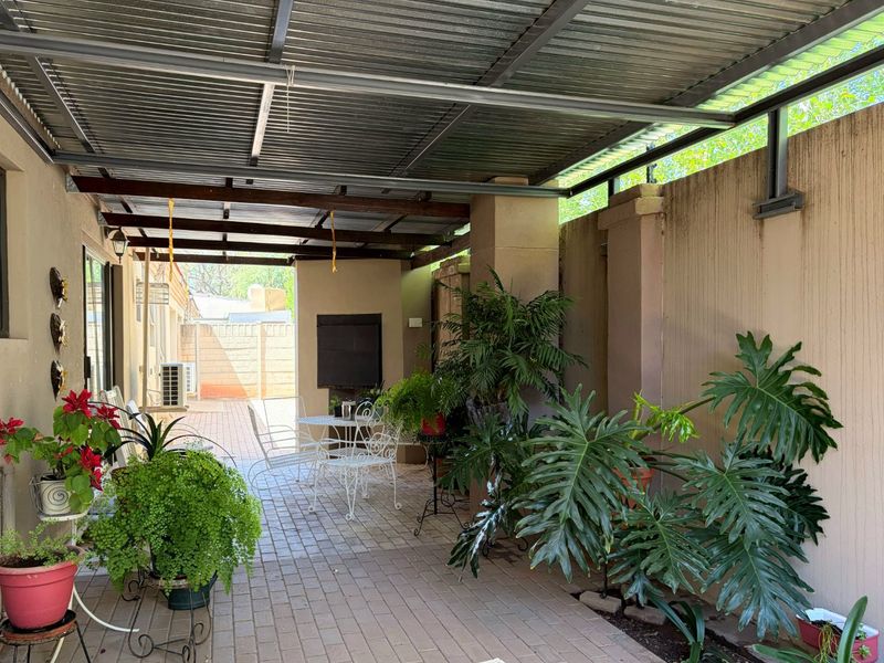 A covered patio area featuring brick paving, a built-in braai, and a corrugated metal roof, providing a functional outdoor entertainment space.