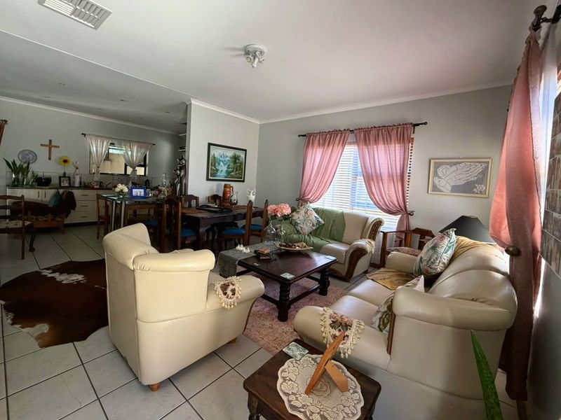 Spacious open-plan living and dining area featuring tiled flooring, neutral wall tones, and an integrated kitchen space with functional cabinetry.