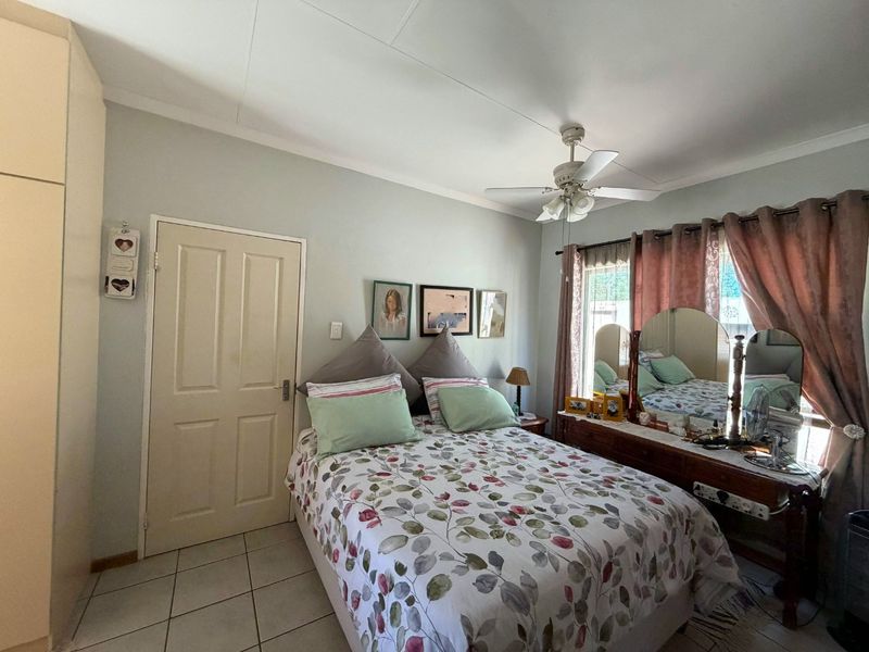 A functional bedroom featuring tiled flooring, a ceiling fan, and a built-in wardrobe, offering a comfortable and practical living space.