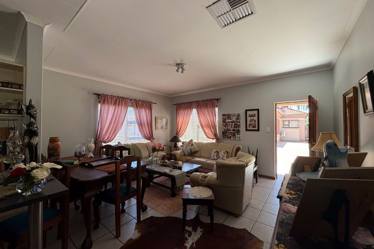 A spacious living room featuring tiled flooring, coving, and direct access to the rear exterior area.