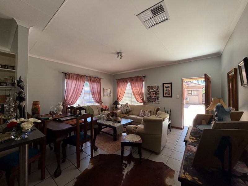 A spacious living room featuring tiled flooring, coving, and direct access to the rear exterior area.