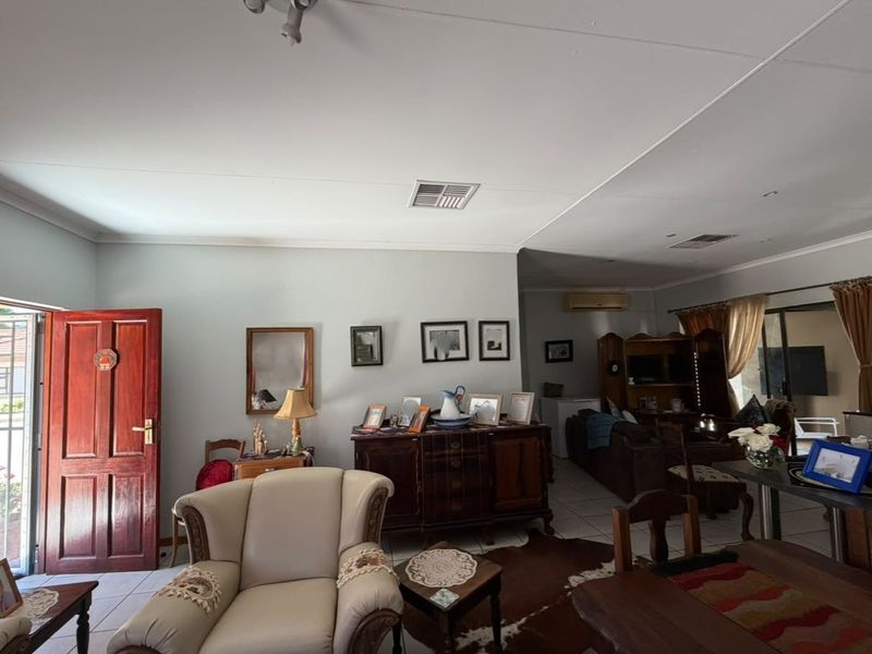 An open-plan living area featuring tiled flooring, ceiling vents, and a sliding glass door leading to the exterior.