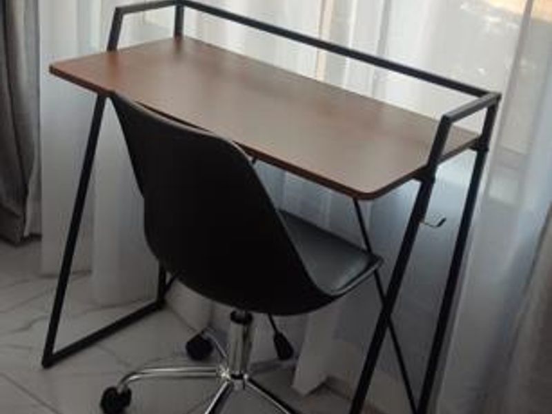A compact workspace area featuring modern tiled flooring and natural light from large windows.