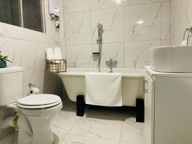Modern bathroom featuring marble-look tiling, a freestanding bathtub with shower mixer, and a vanity basin.