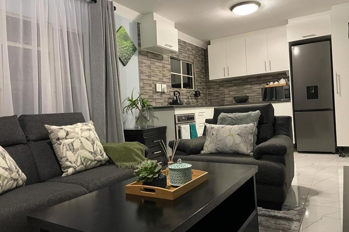 Open plan living area featuring a modern kitchen with built-in cabinetry, tiled backsplash, and integrated oven, seamlessly connected to a comfortable lounge space.