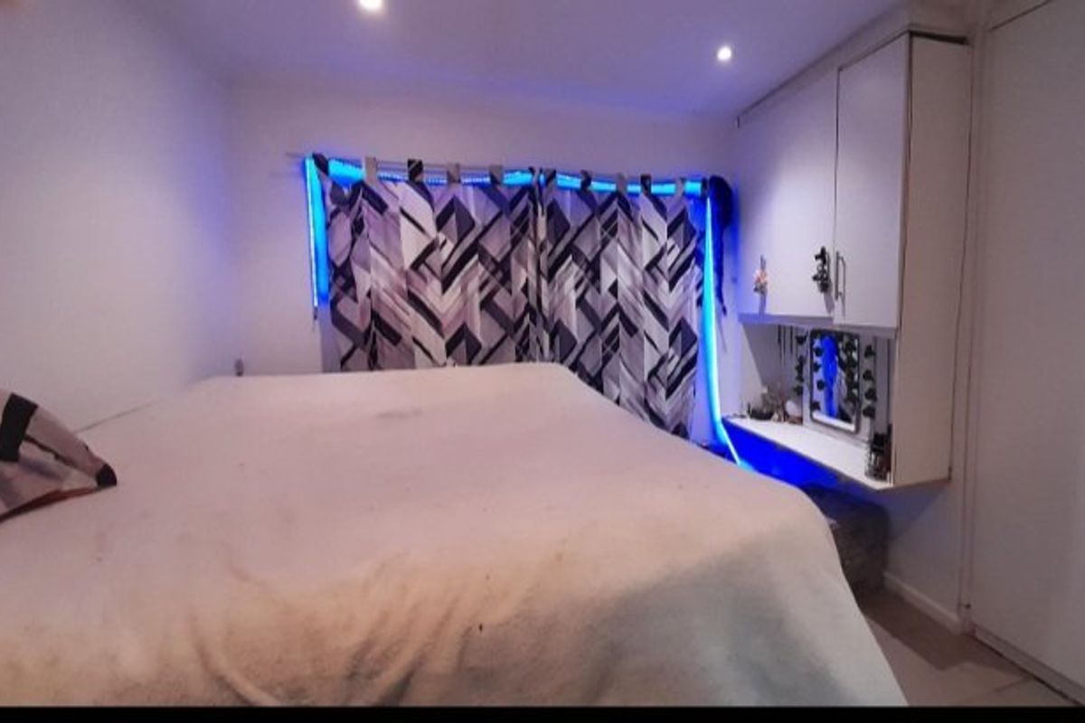 A bedroom featuring built-in cabinetry and a desk area with integrated lighting.