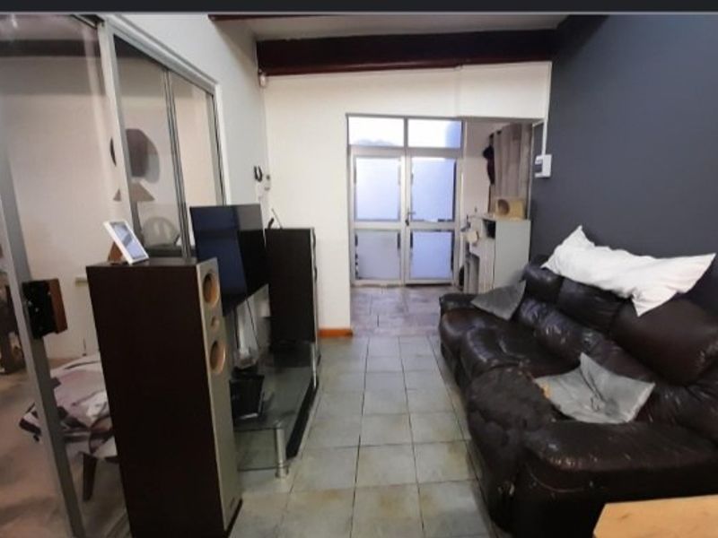 A living area featuring tiled flooring, an exposed ceiling beam, and an aluminium-framed glass door leading to an exterior space.