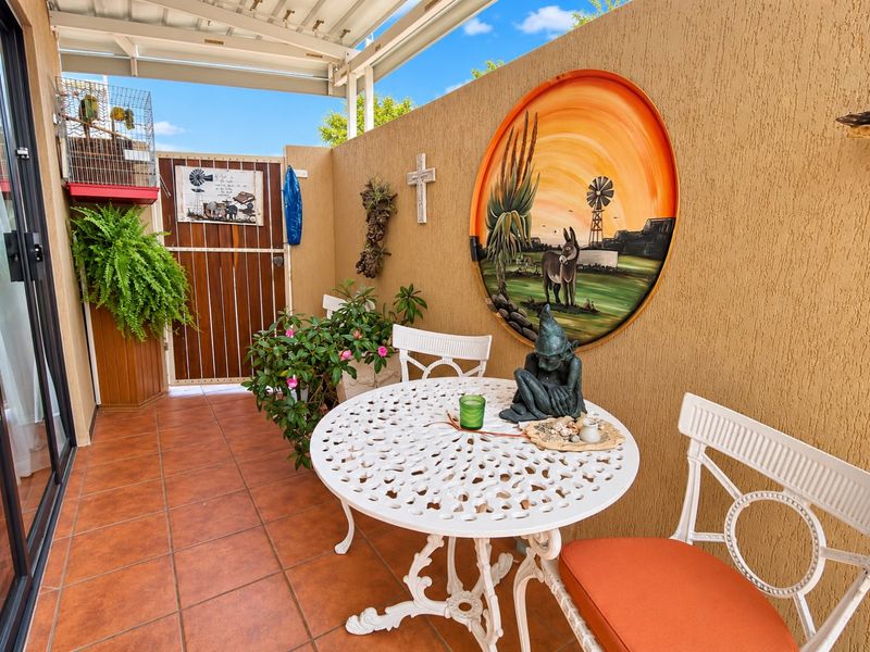 A covered outdoor patio area featuring tiled flooring and a textured wall finish, providing a private and sheltered space for relaxation.