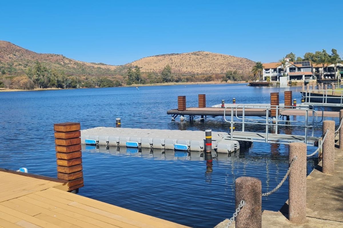Scenic waterfront view featuring a well-maintained floating jetty, wooden decking, and stone bollards overlooking a tranquil lake with mountain vistas.