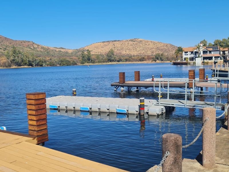 Scenic waterfront view featuring a well-maintained floating jetty, wooden decking, and stone bollards overlooking a tranquil lake with mountain vistas.