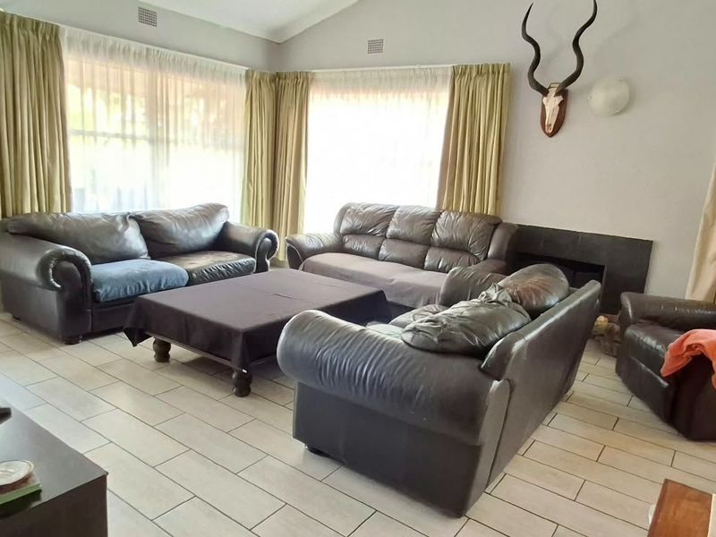 Spacious living room featuring tiled flooring, a vaulted ceiling, and a built-in fireplace, offering a comfortable and functional family area.