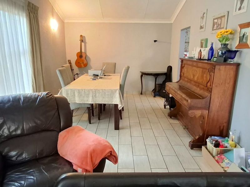 A spacious living and dining area featuring neutral tiled flooring, coved ceilings, and large windows that provide ample natural light.