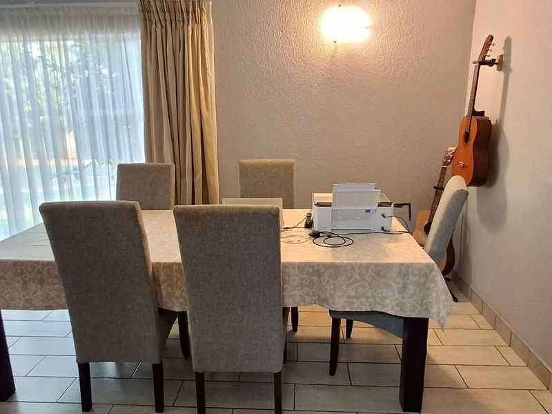 A dining area featuring tiled flooring, a wall-mounted light fixture, and a sliding glass door providing access to the exterior.