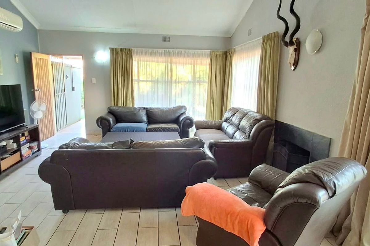A spacious living room featuring tiled flooring, a vaulted ceiling, a built-in fireplace, and a wall-mounted air conditioning unit.