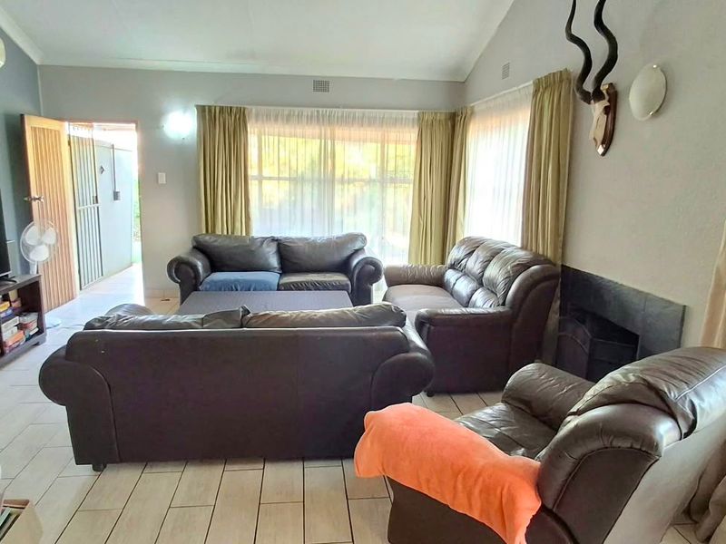 A spacious living room featuring tiled flooring, a vaulted ceiling, a built-in fireplace, and a wall-mounted air conditioning unit.