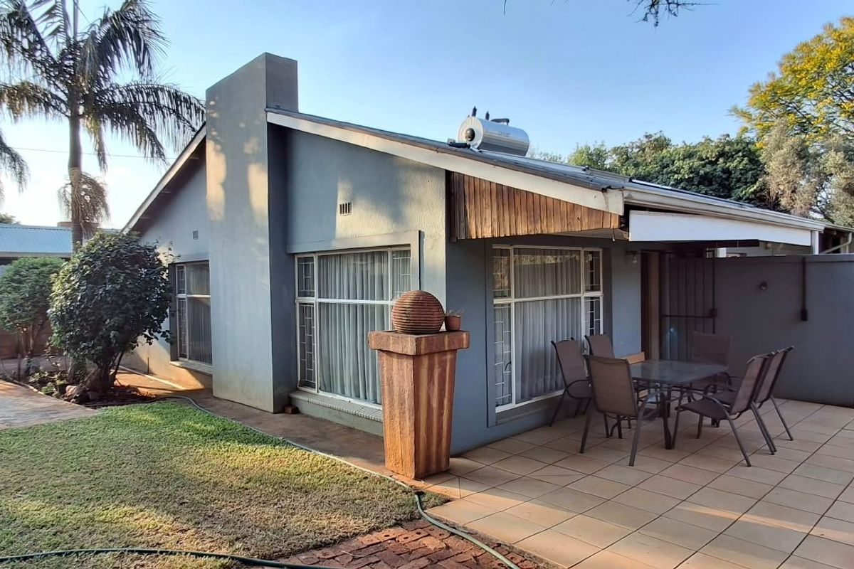 Rear view of the house featuring a tiled patio area, solar water heater, and established garden surroundings.