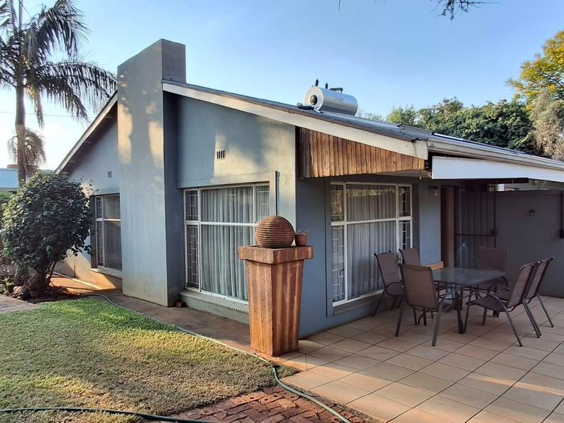 Rear view of the house featuring a tiled patio area, solar water heater, and established garden surroundings.
