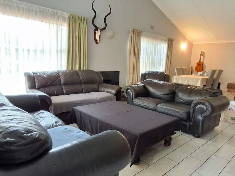 Spacious open-plan living and dining area featuring tiled flooring, a vaulted ceiling, and a built-in fireplace, offering a comfortable and functional layout.