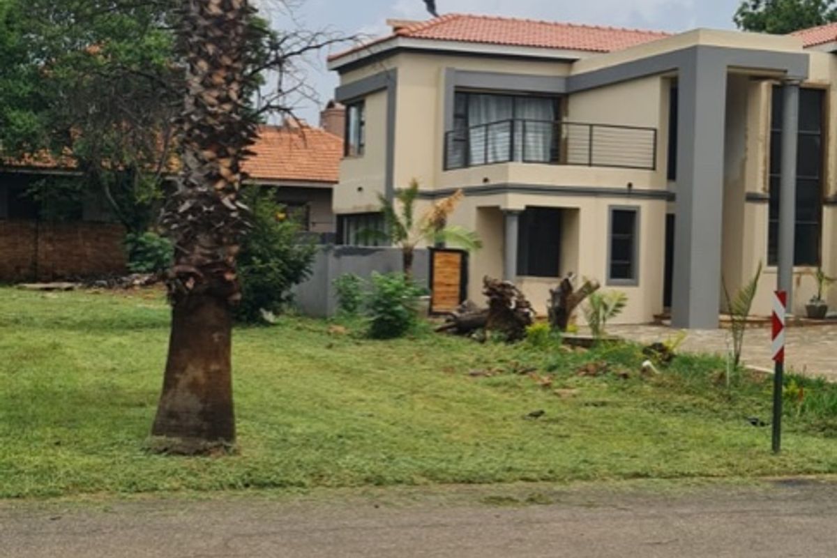 A view of the front elevation of a two-story residential property featuring a tiled roof, balcony, and paved driveway area.