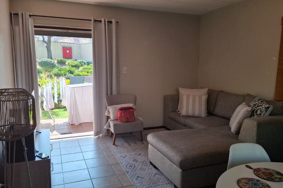 A living room featuring tiled flooring and a sliding glass door providing direct access to an outdoor patio area.