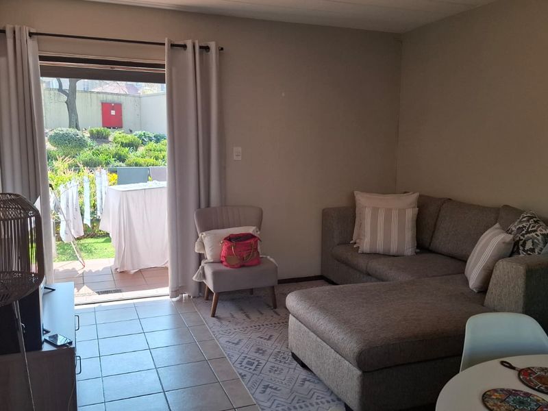 A living room featuring tiled flooring and a sliding glass door providing direct access to an outdoor patio area.