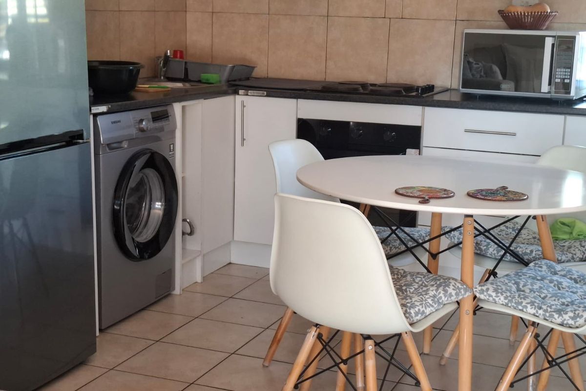 A functional kitchen featuring built-in cabinetry, dark countertops, a built-in oven and hob, tiled backsplash, and tiled flooring with integrated laundry plumbing.