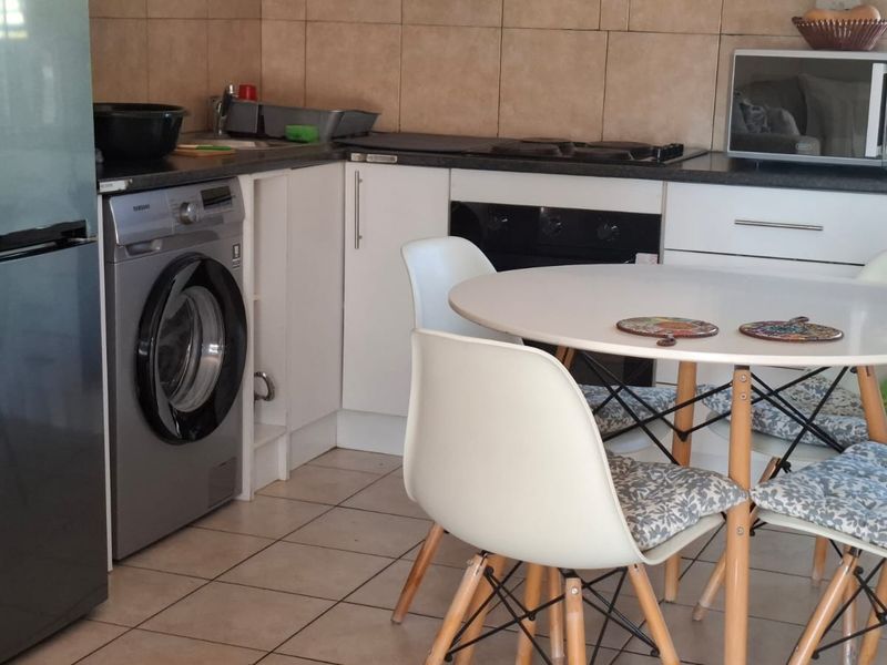 A functional kitchen featuring built-in cabinetry, dark countertops, a built-in oven and hob, tiled backsplash, and tiled flooring with integrated laundry plumbing.