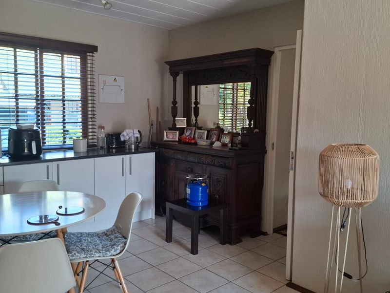 Open plan kitchen and dining area featuring tiled flooring, white cabinetry, and venetian blinds, offering a functional layout for daily living.