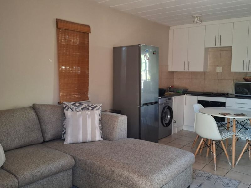 Open-plan living and kitchen area featuring white cabinetry, tiled flooring, and a functional layout suitable for modern apartment living.