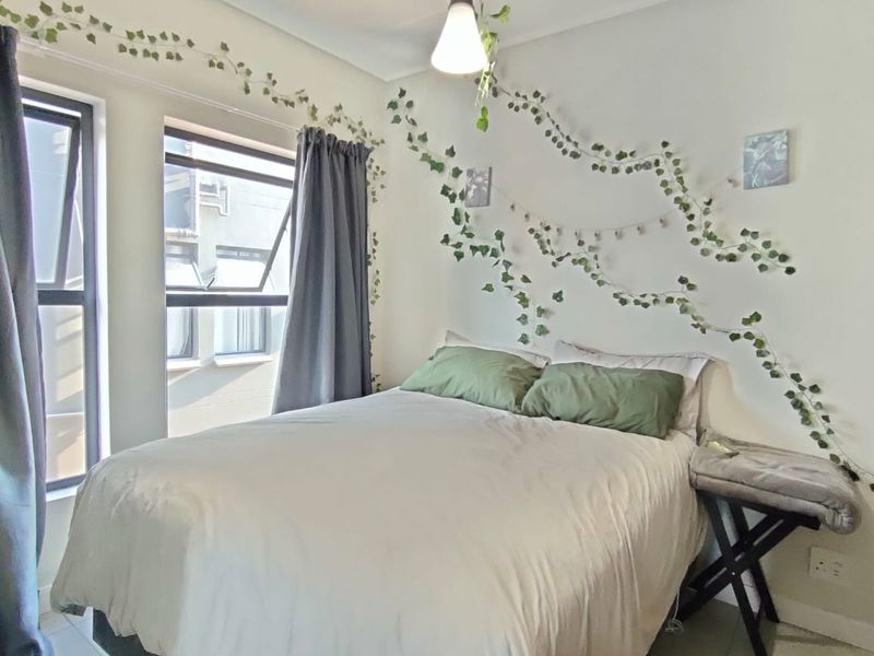 A well-lit bedroom featuring tiled flooring, neutral walls, and large casement windows that provide ample natural light.