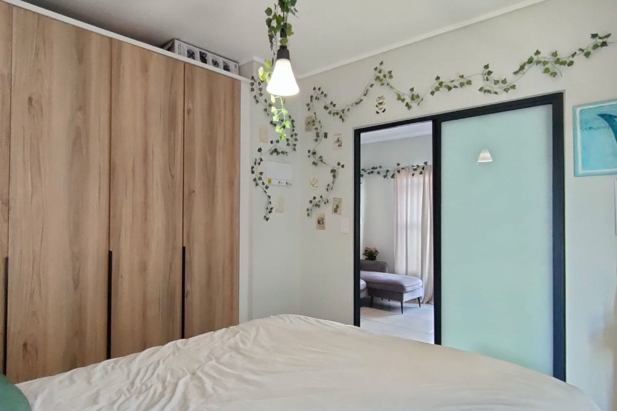 A well-maintained bedroom featuring modern wood-finish built-in wardrobes and a sleek sliding door leading to an adjacent space.